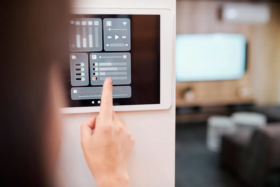 Person steuert Heizung, Licht und Musik über ein Smart-Home-Touchpanel an der Wand